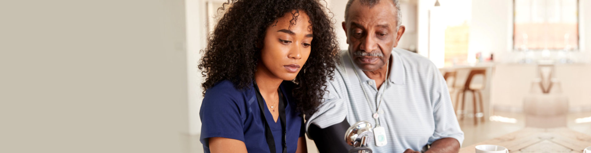 skilled nurse checking the blood pressure of an elderly man at home