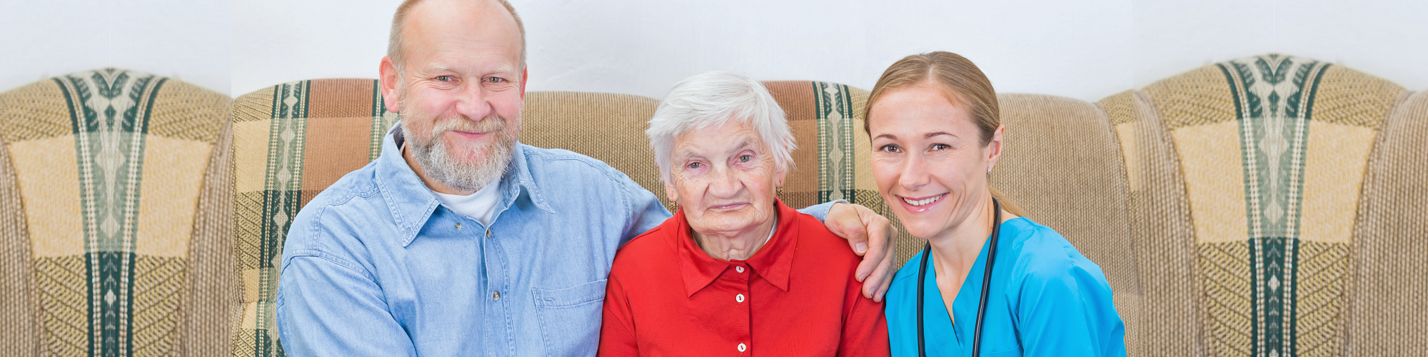 a chaplain, an elderly woman, and a nurse sitting on the sofa together and smiling