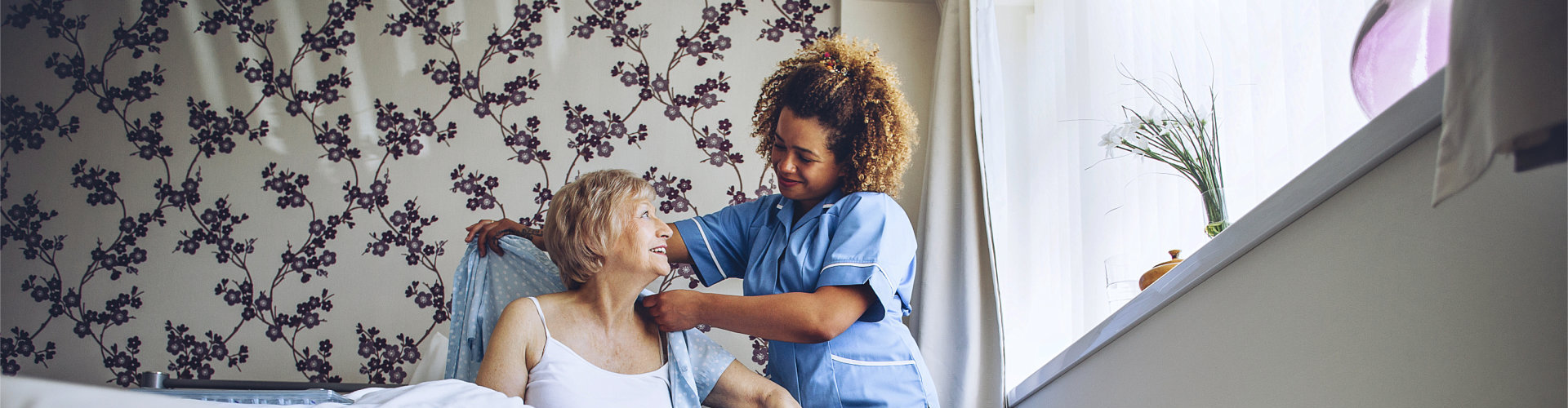 caregiver helping senior woman dress up